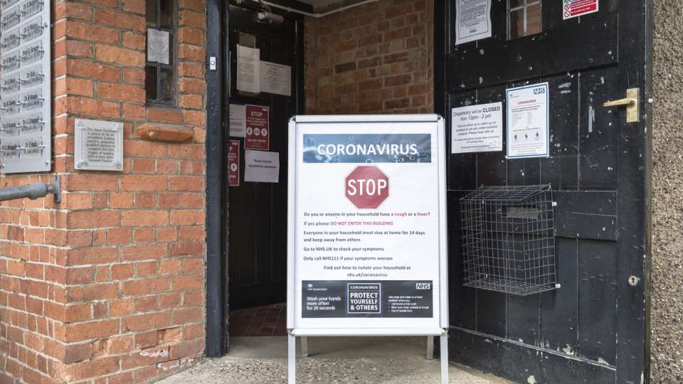 Coronavirus COVID-19 warning sign with prevention information outside a GP doctor surgery