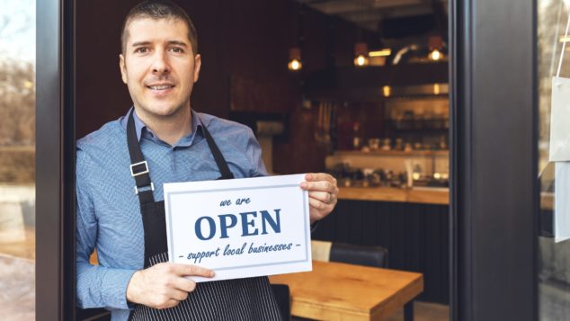 Cafe owner holding Open sign, reopening your small business after lockdown concept